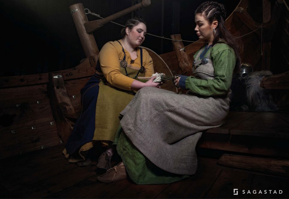 Two female Vikings doing tablet weaving in the Myklebust ship.